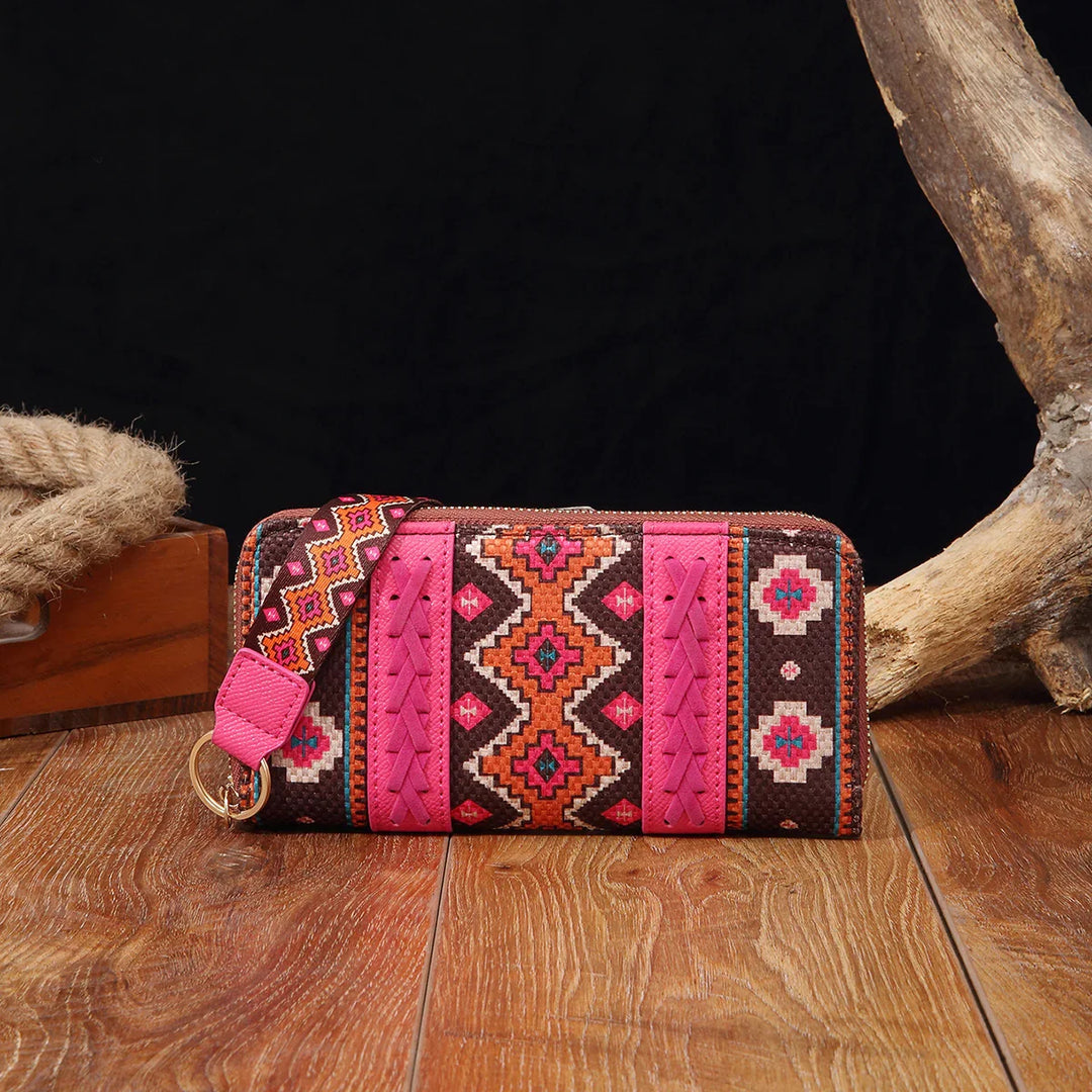 Colorful pink and brown tribal-patterned wristlet wallet on wooden surface with rustic decor