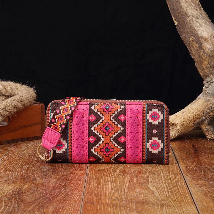 Colorful pink and brown tribal-patterned wristlet wallet on wooden surface with rustic decor