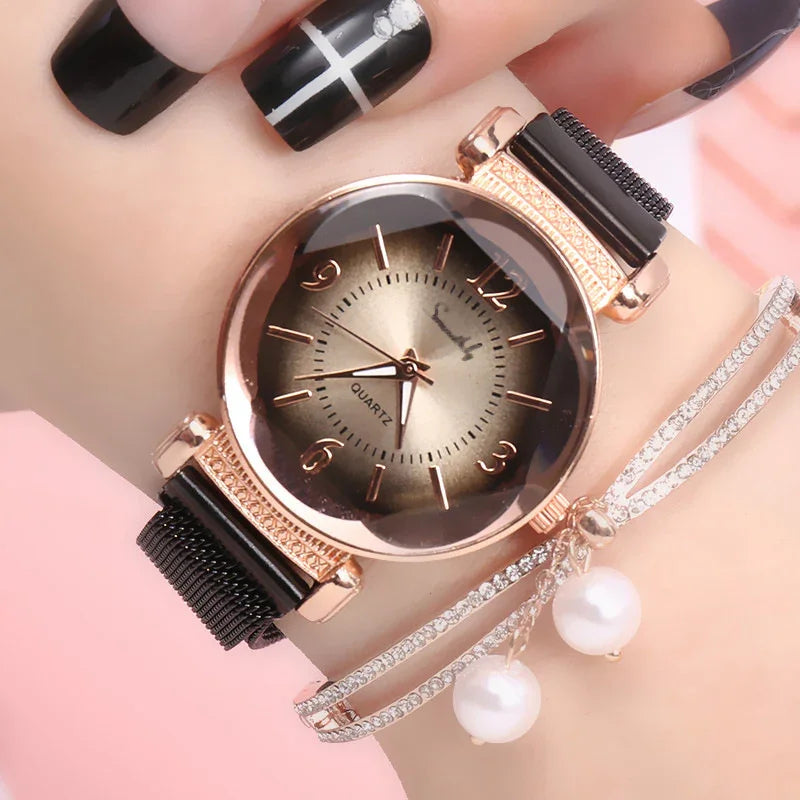 Close-up of wrist with rose gold quartz watch, black mesh strap, and rhinestone bracelet with pearl charms