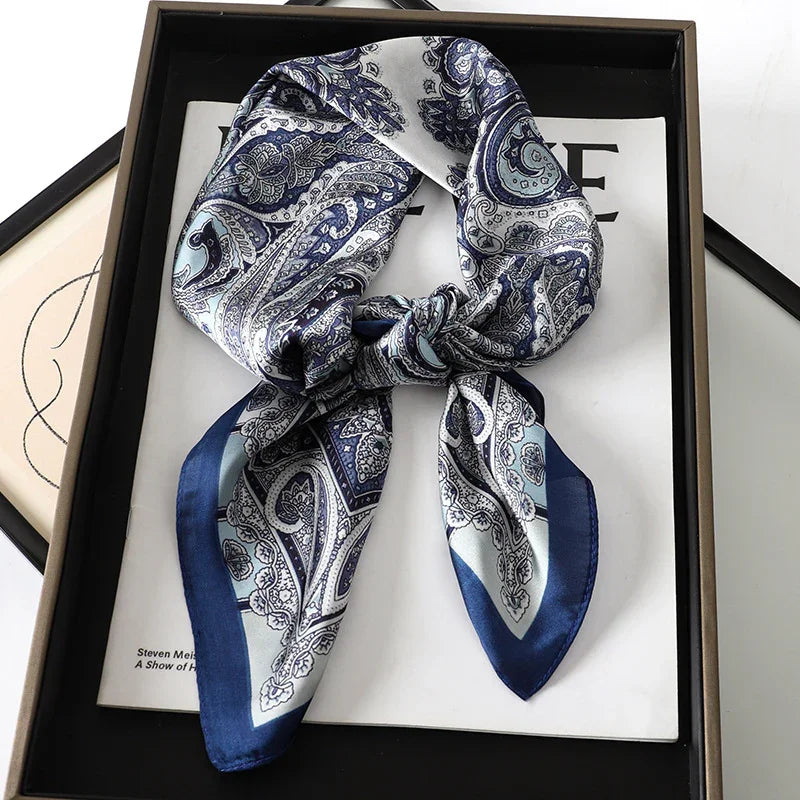Blue and white paisley silk scarf tied and displayed on a black tray with books underneath