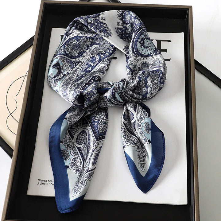 Blue and white paisley silk scarf tied and displayed on a black tray with books underneath