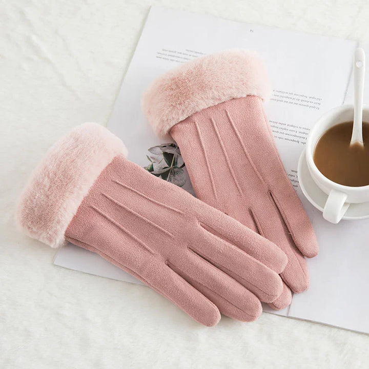 Soft pink winter gloves with fur cuffs on white surface near coffee cup and open book
