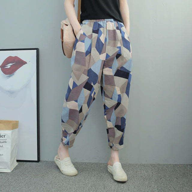 Woman wearing geometric patterned loose pants in blue and beige tones with white slip-on shoes