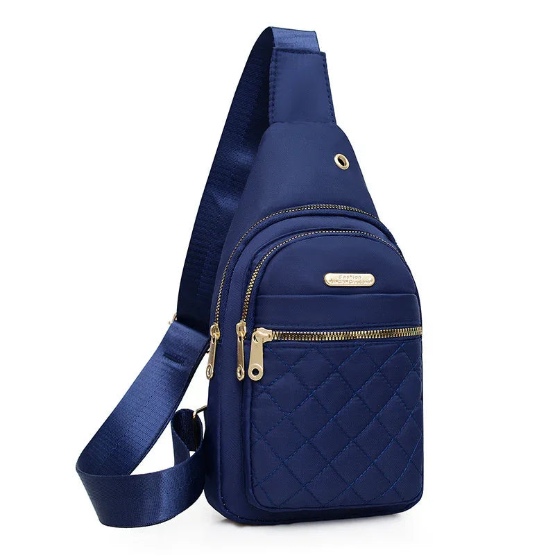 Navy blue quilted sling backpack with gold zippers and adjustable strap