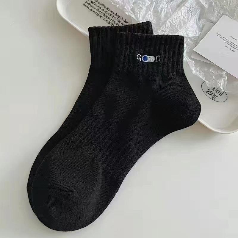 Pair of black ankle socks with ribbed cuffs and 'GOOD' embroidery on white tray