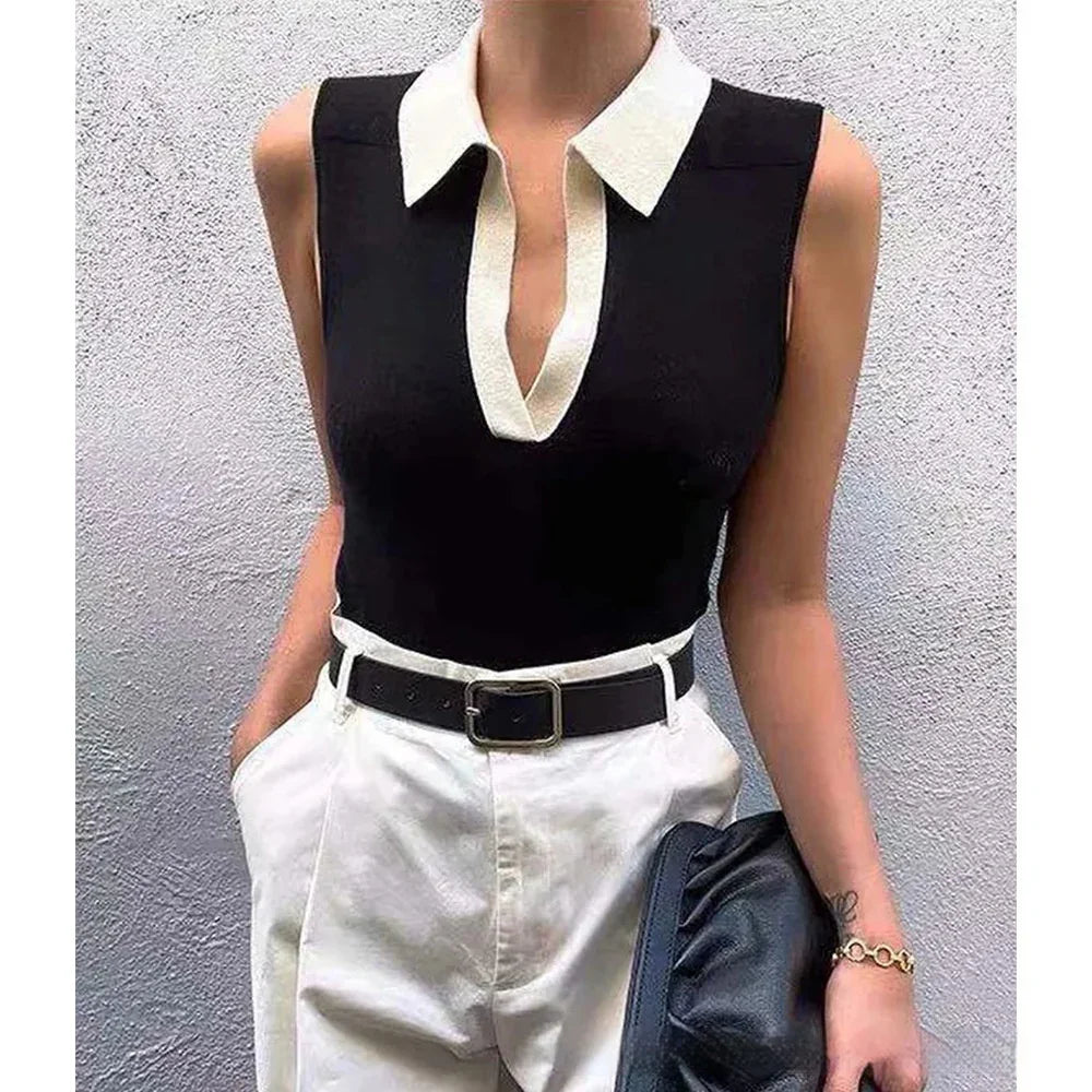 Woman wearing sleeveless black top with white collar and white high-waisted pants holding black clutch