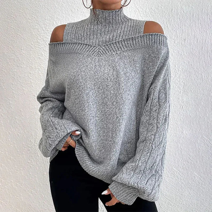 Woman wearing gray off-shoulder cable knit sweater with high neck and black pants