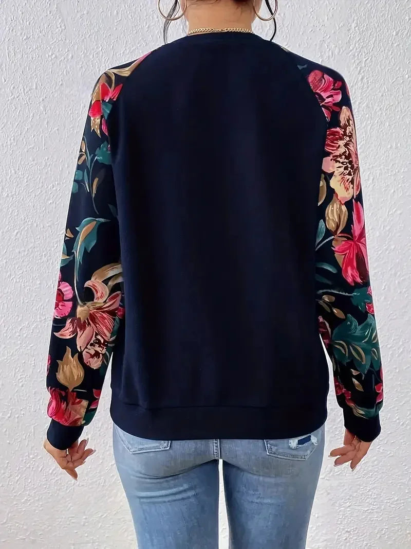 Woman wearing navy pullover with floral print sleeves and light blue jeans from back