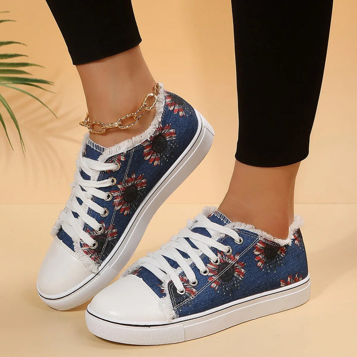 Women's denim sneakers with white toes, floral print, frayed edges, and white laces