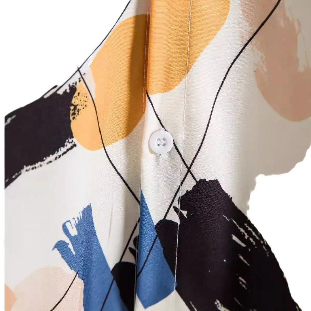 Close-up of fabric with abstract yellow, blue, and black brushstroke pattern and white button detail