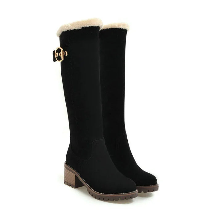 Black knee-high winter boots with faux fur trim and chunky brown heels and soles