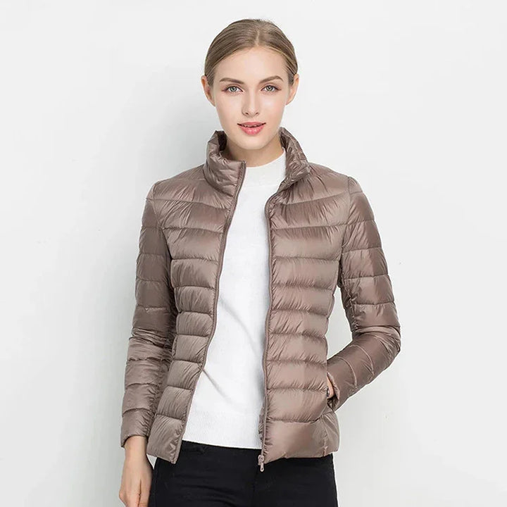 woman wearing light brown quilted puffer jacket with high collar and white sweater