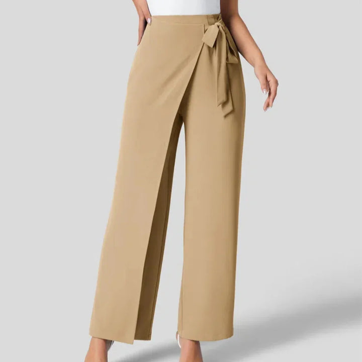 Beige wrap-front wide leg pants with side tie detail on model against gray background