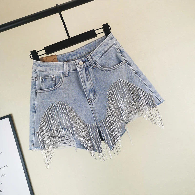 Light blue denim shorts with silver rhinestone fringe detail hanging on black hanger