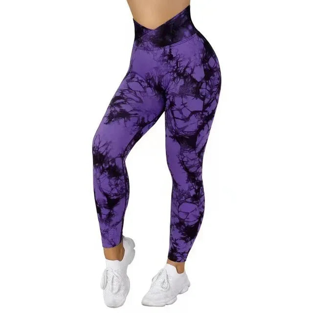 Women's high-waisted purple and black tie-dye leggings with white athletic shoes