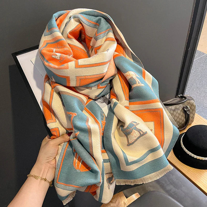 Soft scarf with blue, orange, and cream geometric patterns and horse motifs, held by hand
