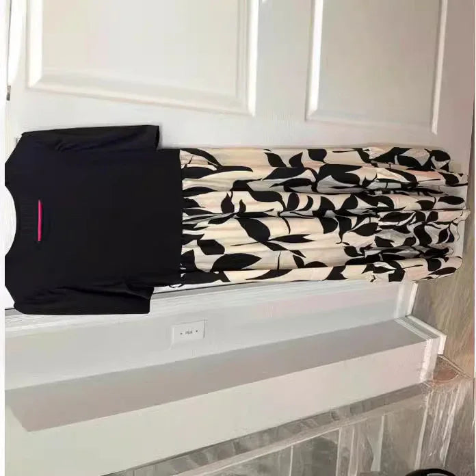 Black top paired with a high-waisted cream skirt featuring large black leaf patterns, hanging on a white door