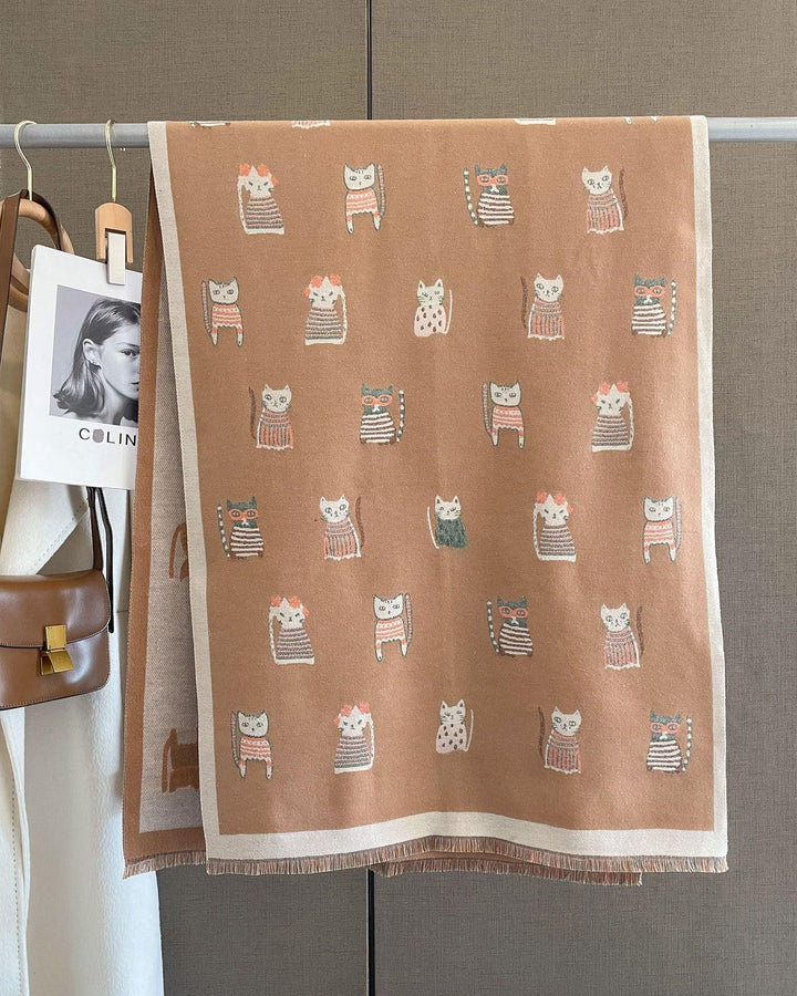Beige and brown scarf with cartoon cat patterns hanging on clothing rack