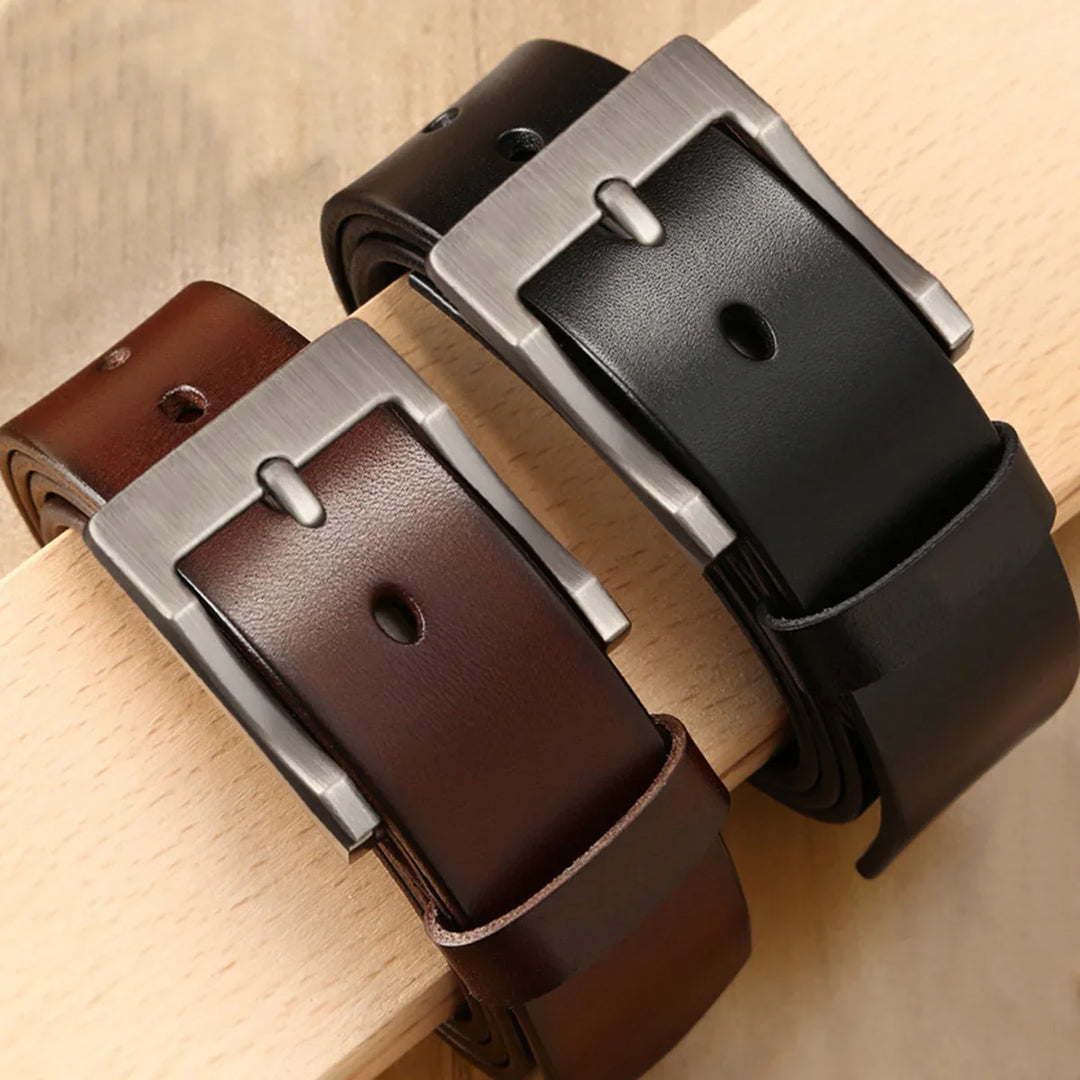 Two leather belts in brown and black with silver buckles on wooden surface