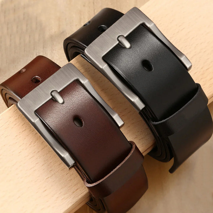 Two leather belts in brown and black with silver buckles on wooden surface