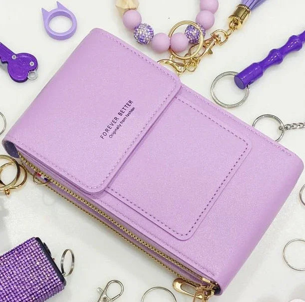Lavender purple wallet with gold zipper and text surrounded by purple keychains and accessories