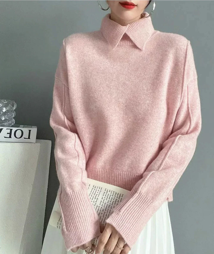 Woman wearing soft pink knit sweater with wide collar and long ribbed sleeves holding a book