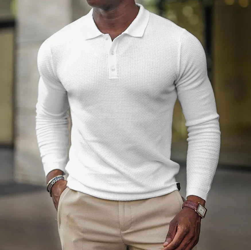 Man wearing a fitted white long-sleeve polo shirt and beige pants outdoors, accessory bracelets and watch