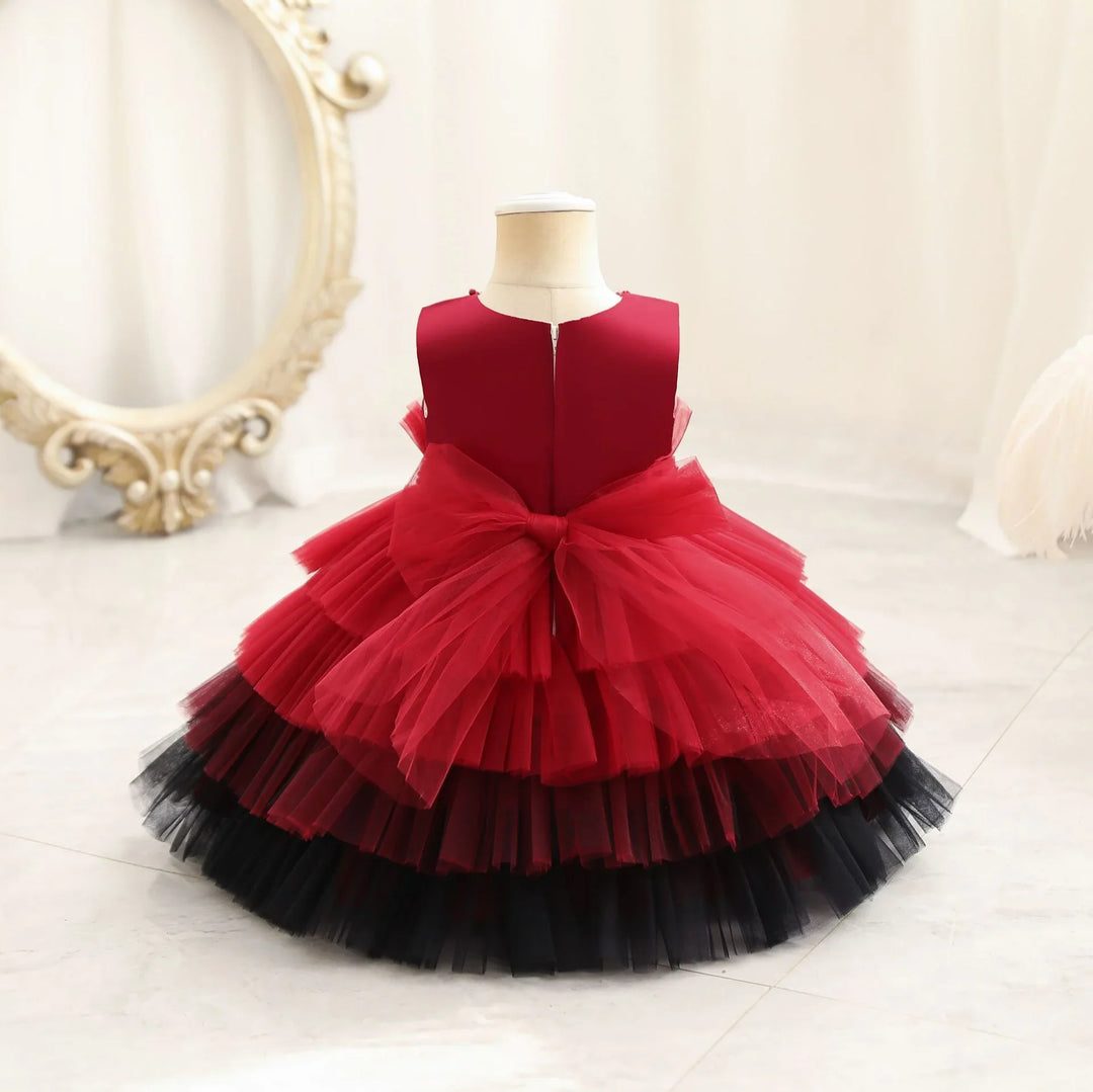 Red and black layered tulle dress with a large bow displayed on a mannequin in a bright room
