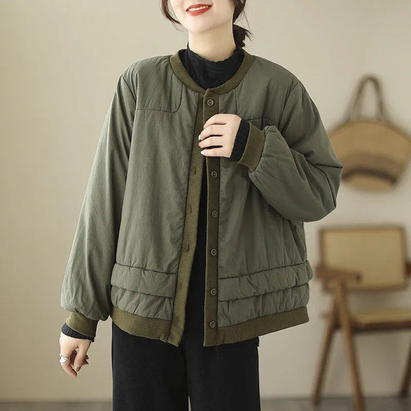 Woman wearing olive green button-up padded jacket with ribbed cuffs and hem in cozy indoor setting