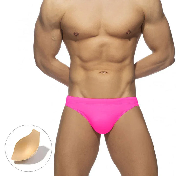 Muscular male torso wearing bright pink men's bikini briefs with beige removable padding shown