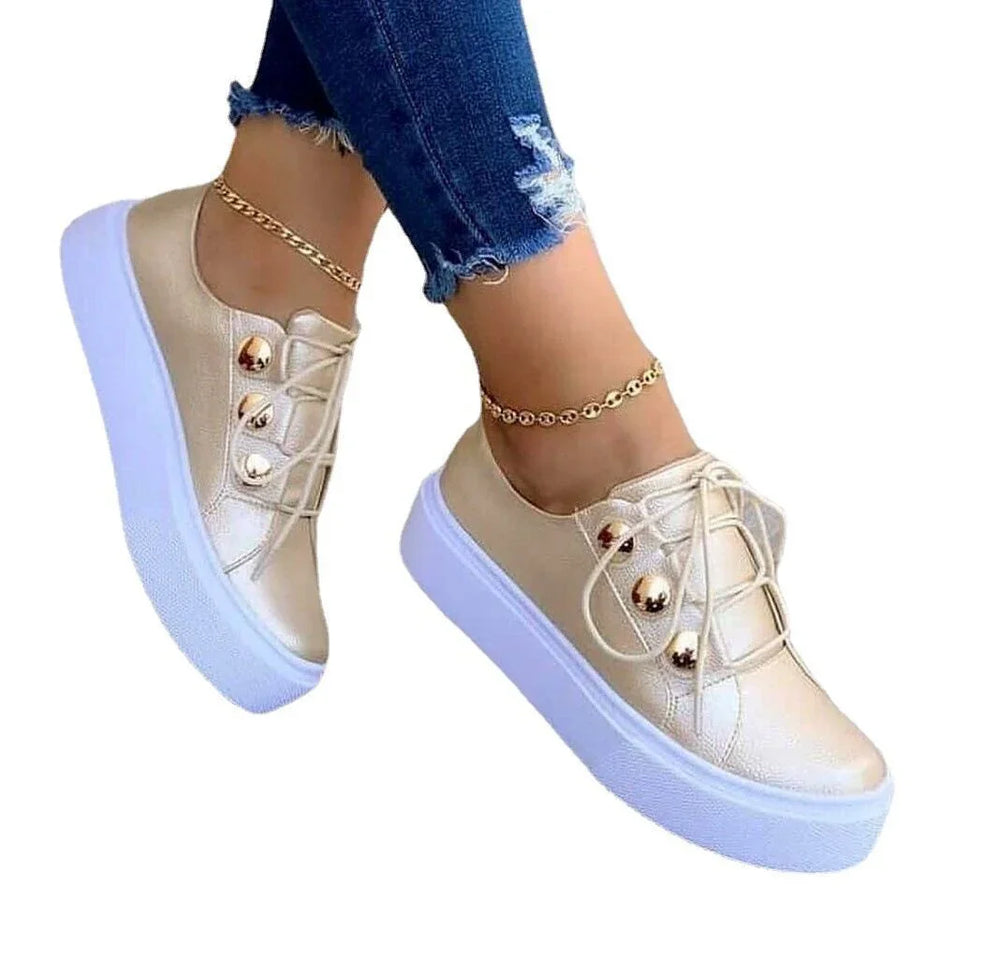 Women wearing metallic gold platform sneakers with white thick soles and gold ankle bracelets, paired with ripped blue jeans