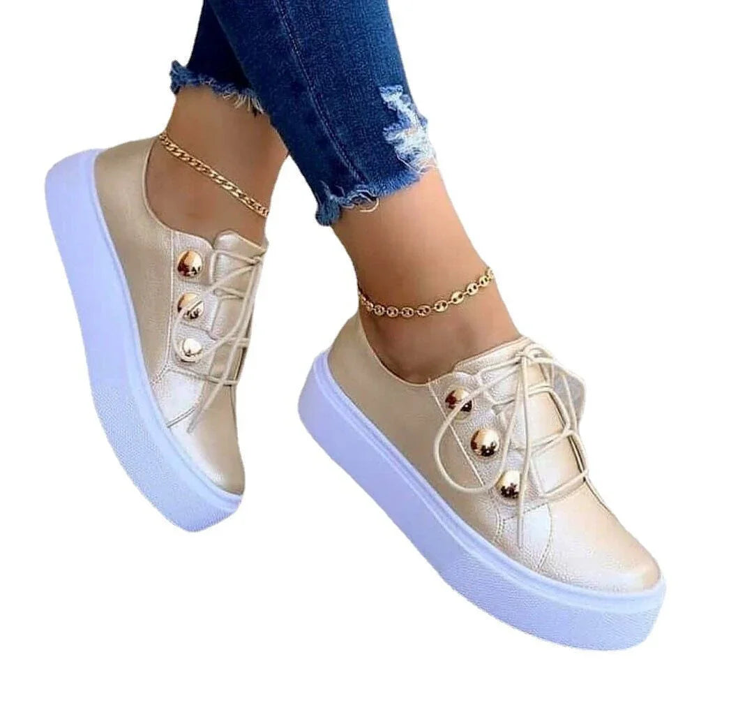 Women wearing metallic gold platform sneakers with white thick soles and gold ankle bracelets, paired with ripped blue jeans