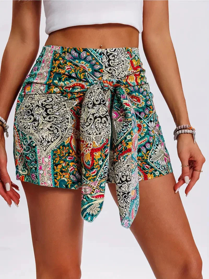 Woman wearing vibrant high-waisted bohemian print shorts with front tie detail and white crop top