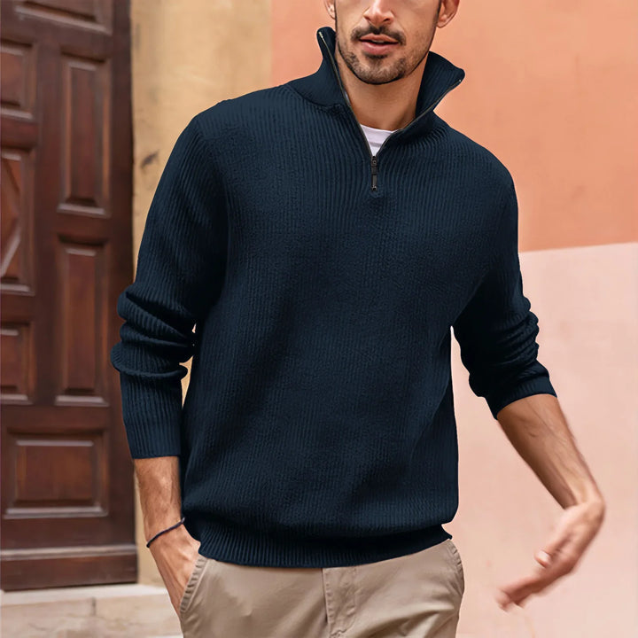 Man wearing a navy blue ribbed half-zip sweater and khaki pants standing outdoors