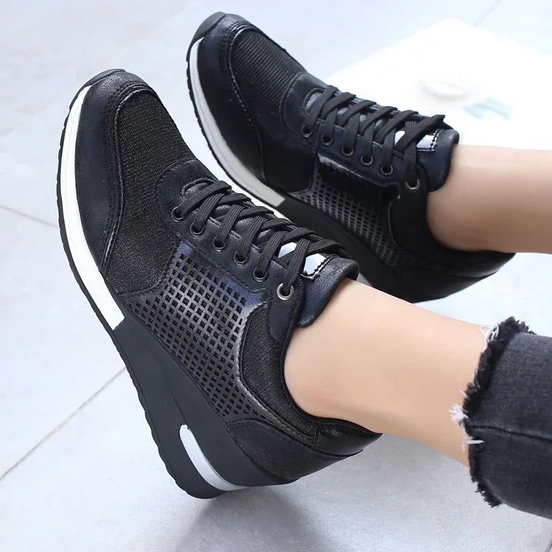 Black stylish platform sneakers with mesh and lace-up design worn with frayed black jeans on gray floor