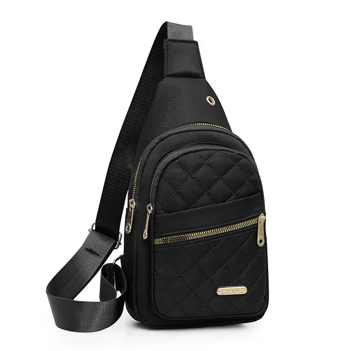 Black quilted sling bag with gold zippers and adjustable strap on white background
