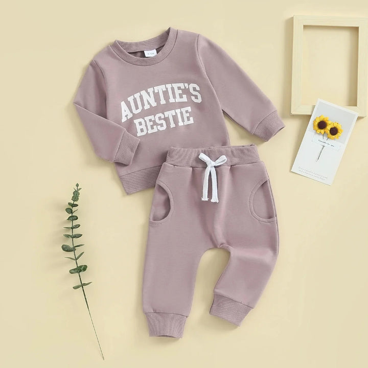 Mauve baby outfit with 'Auntie's Bestie' sweatshirt and matching pants on beige background
