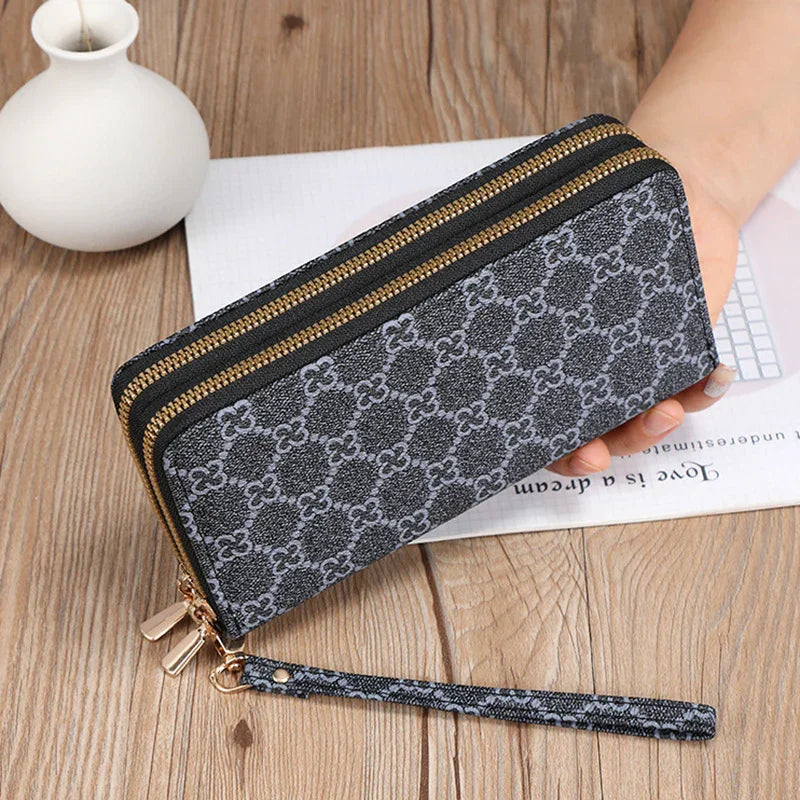 Stylish gray patterned zip-around wallet with wrist strap on wooden surface