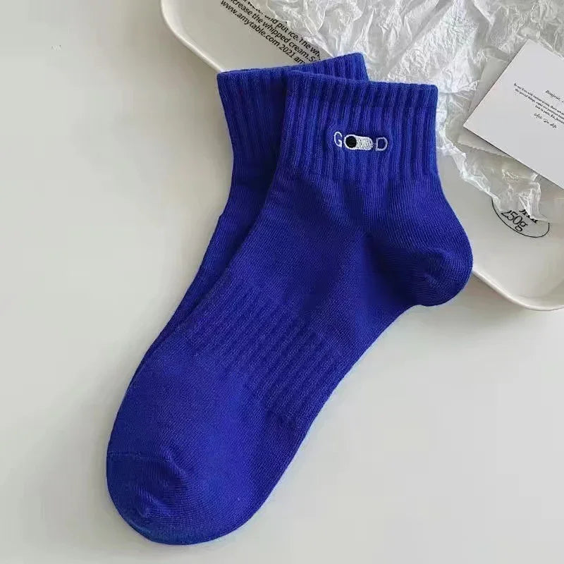 Pair of royal blue ankle socks with ribbed cuffs and white embroidered 'GOOD' text