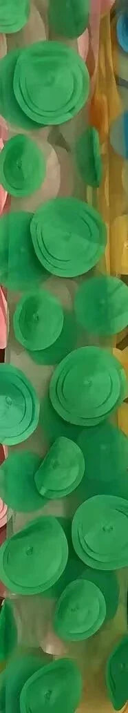 Colorful layered paper roses in green, pink, yellow, and blue arranged vertically on display