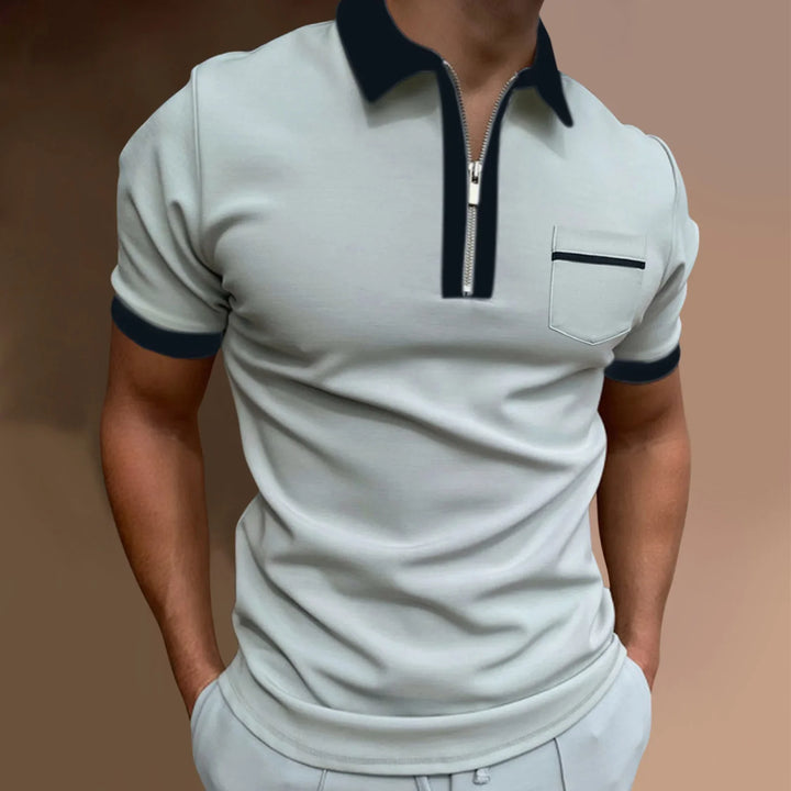 Man wearing light gray polo shirt with black collar, zipper, sleeve cuffs, and chest pocket detail