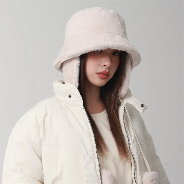 Woman in white fluffy bucket hat and white puffer jacket on gray background