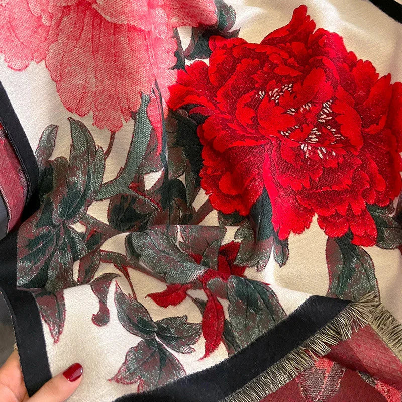 Close-up of fabric with large red and pink peony floral print and green leaves on cream background