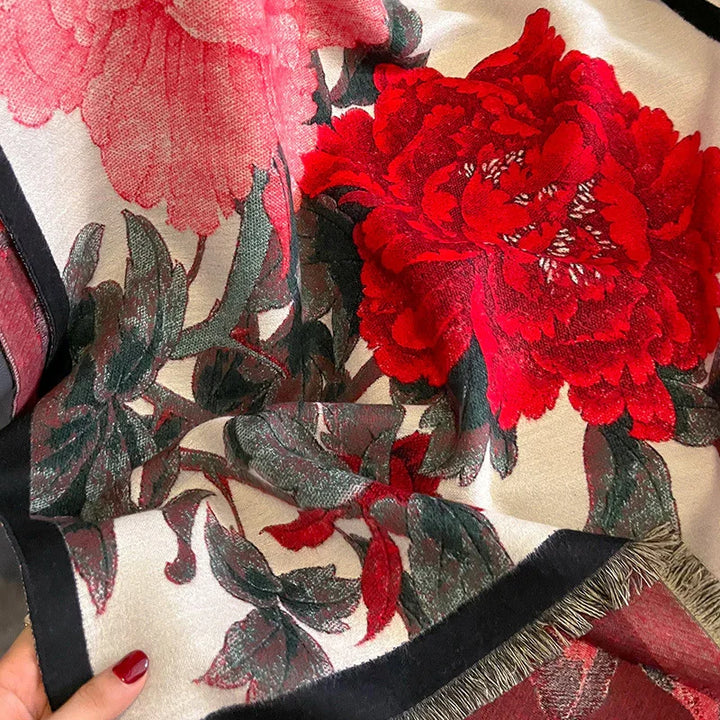 Close-up of fabric with large red and pink peony floral print and green leaves on cream background