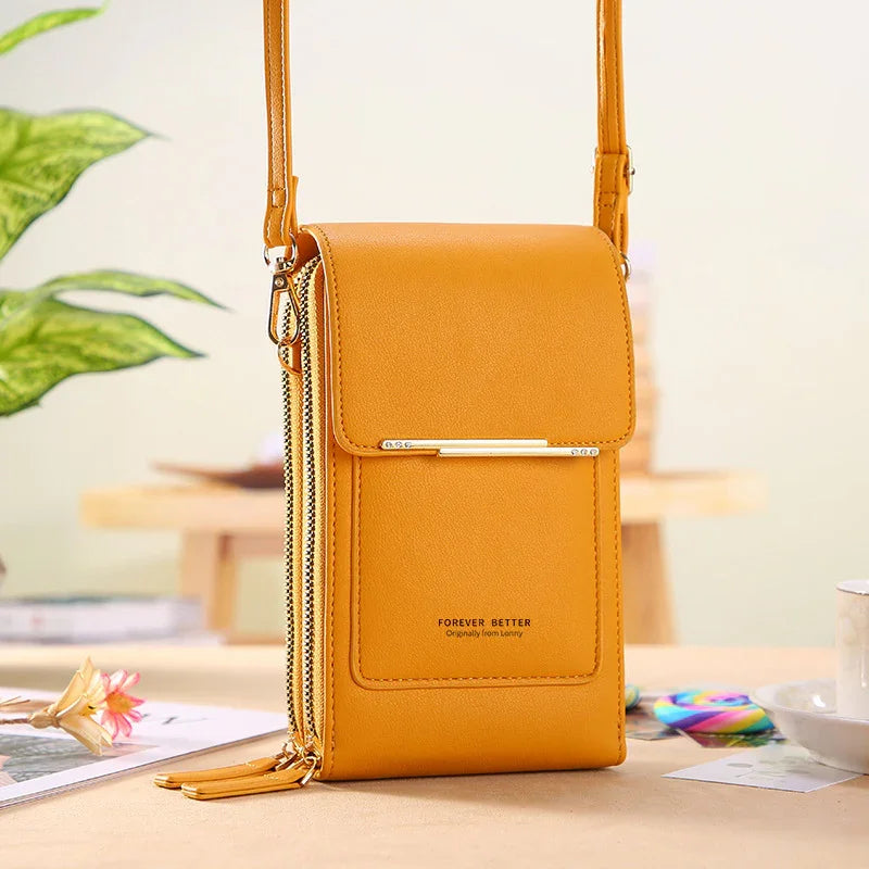 Yellow leather crossbody bag with gold zipper and strap, on a wooden table with decorative items