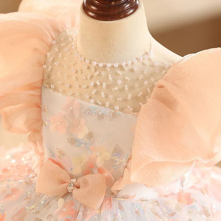 Close-up of peach puff sleeve dress with pearl beading and floral sequin details on mannequin