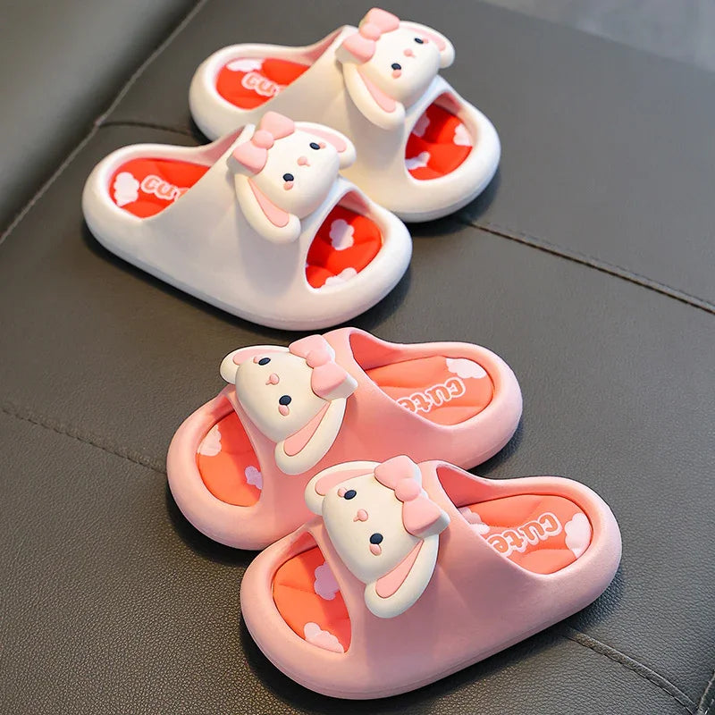 Cute pink and white children's slippers with bunny faces and bows on a gray surface