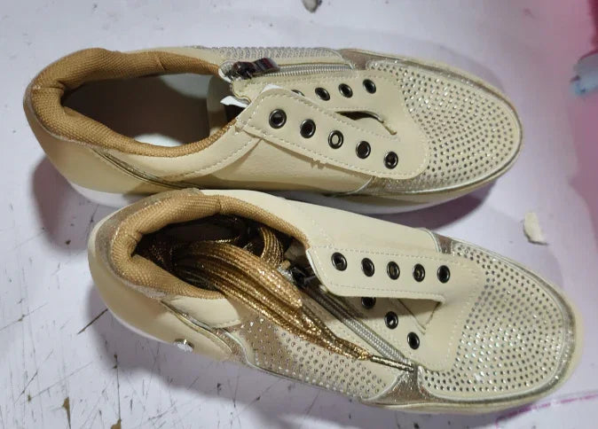 Pair of beige women's sneakers with rhinestone-studded toe caps and gold laces on white surface