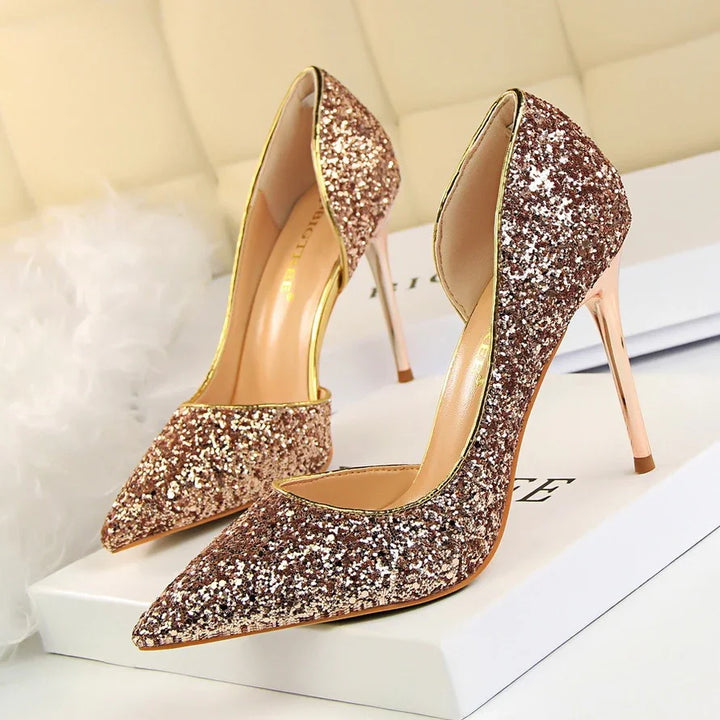 Pair of glittery rose gold high heel stiletto shoes with pointed toes on white box