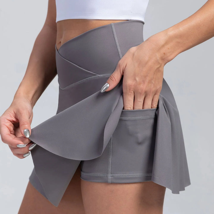 Close-up of woman wearing gray high-waisted athletic skort with built-in shorts and side pocket